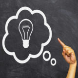 Finger pointing to a light bulb in a thought bubble
